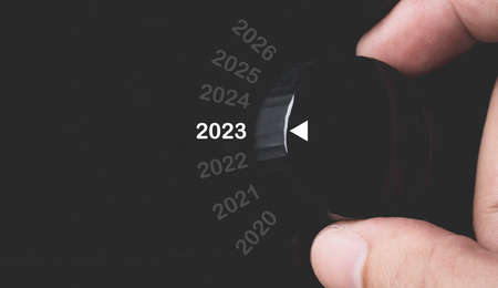 Hand rotate black knob to select 2023 year for preparation Merry Christmas and Happy new year concept.の写真素材