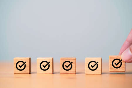 Hand putting and array correct sign which print screen on wooden cube block for approve document and project concept.の写真素材