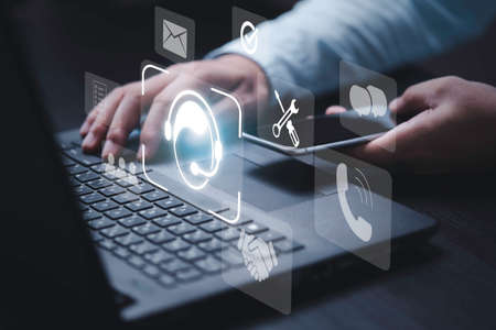 Businessman holding smartphone and using computer laptop to calling to operator and inform trouble shooting of computer concept.の写真素材