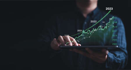 Investor holding tablet with increasing stock market graph chart for trader technical analysis concept.の写真素材