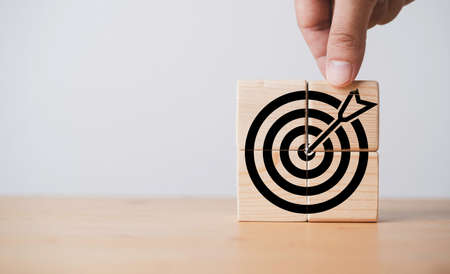Hand assemble black dartboard with arrow which print screen on wooden block for setup business objective target and goal concept.の写真素材