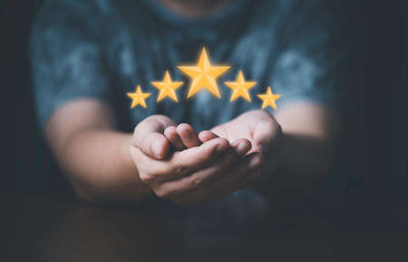 Businessman showing glowing yellow five stars for excellent evaluate after customer use product service , ISO and quality standard certificate concept.の写真素材