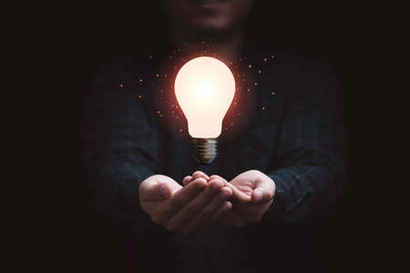 Businessman holding glowing lightbulb for creative thinking innovation idea and problem solving concept.の写真素材