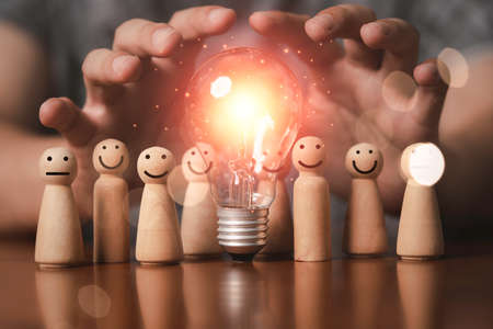Many wooden figure around of glowing lightbulb for brainstorming and teamwork can creative thinking...