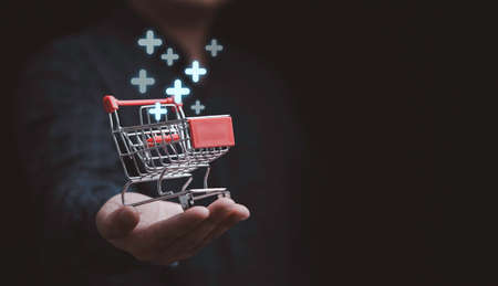 Businessman hand holding trolley cart shopping cart with plus sign symbol to add or receive order , Technology online shopping business concept.の写真素材