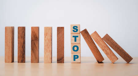 Stop wording print on wooden block cube protect wooden falling domino for risk management concept.の写真素材