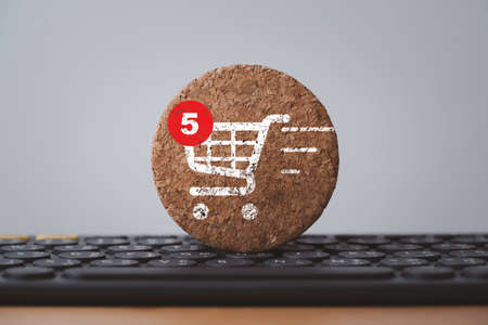 Shopping trolley cart and notification print screen to round wooden block on computer keyboard for online shopping and e-commerce business concept.の写真素材
