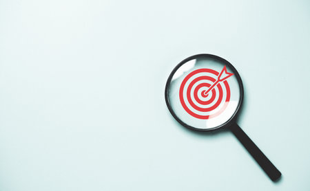 Red dartboard inside of black magnifier glass on blue background for setup objective target and business goal concept.の写真素材