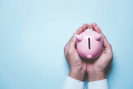 Top view of hand holding pink piggy bank deposit  for deposit banking of investment , retirement to get profit and interest concept.の写真素材