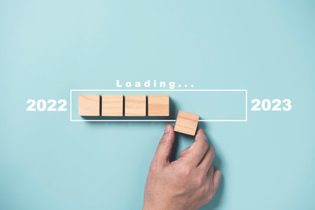 Businessman array wooden cube block with virtual loading bar for count down from 2022 to 2023 year of preparation merry Christmas and happy new year by technology download concept.の写真素材