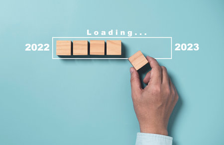 Businessman array wooden cube block with virtual loading bar for count down from 2022 to 2023 year of preparation merry Christmas and happy new year by technology download concept.の写真素材