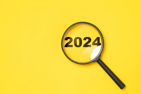 2024 year inside of magnifier glass on yellow background for focus and preparation new year change and start new business target strategy concept.の写真素材