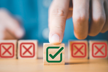 Hand pushing green correct sign symbol in front of Red Cross sign on wooden block cube for business proposal and document approve concept.の写真素材