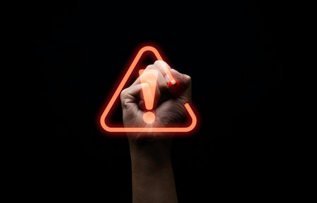 Hand writing red triangle caution exclamation warning sign for notification error and maintenance concept.の写真素材