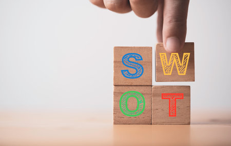 Hand putting S W O and T alphabet which print screen on wooden cube block for business marketing analysis including Strength Weakness Opportunities  and Threats concept.の写真素材
