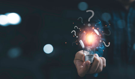 Businessman holding glowing lightbulb and question mark with copy space for creative thinking idea and problem solving concepの写真素材