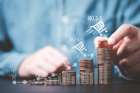 Businessman stacking  increasing coins with trend graph of sale volume and bigger shopping trolley cart for  online sale business growth concept.の写真素材