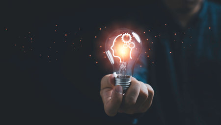 Businessman holding glowing lightbulb and human icon thinking with copy space for creative thinking idea and problem solving concept.の写真素材