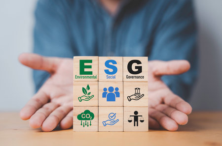 Businessman hand give  ESG wording on wooden cube block for sustainable organization development and corporation of Environment Social Governance concept.の写真素材