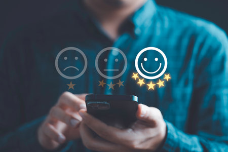 Businessman using smartphone to give five glowing golden stars and smile face icon for excellent evaluation survey after client use product and service from customer satisfaction concept.の写真素材
