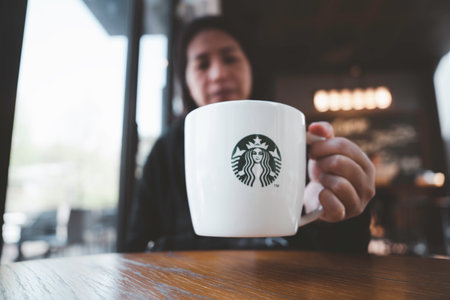 Seoul , South Korea - April 12, 2023 : Close up woman holding Starbuck coffee cup with blur Starbuck coffee cafe  background ,Starbucks is the world's largest coffee franchise.のeditorial素材