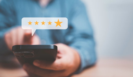 Businessman using smartphone for giving golden five stars for excellent evaluate after customer use product service , ISO and quality standard certificate concept.の写真素材
