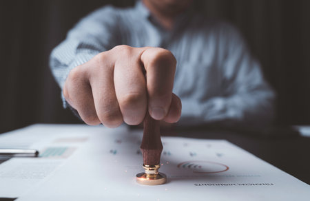 Closeup of businessman hand stamping approve project and quality document on desk , Certificate and ISO concept.の写真素材