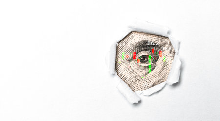 Closeup Benjamin Franklin eye on USD banknote with stock market chart graph behind punch paper for currency exchange and global trade forex concept.の写真素材
