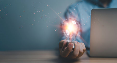 Hand holding the glowing lightbulb that is illuminating for creative thinking idea of problem solving , patent and innovation concept.の写真素材