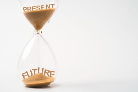 Present wording dropping from top of hourglass to future wording   and future inside of sand clock on white background with copy space for continuous improvement concept.の写真素材