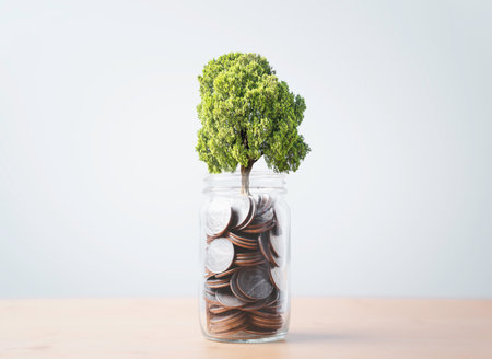 Green tree growth inside of coins money  jar for money saving deposit investment to get increasing profit and dividend concept.の写真素材