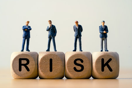 Businessmen miniature figures standing and thinking on risk wording which print screen on wooden cube block for risk management and assessment concept.の写真素材