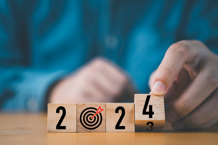 Businessman flipping of 2023 to 2024 on wooden block cube for preparation new year change and start new business target strategy concept.の写真素材