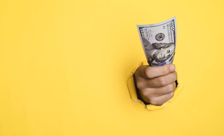 Businessman holding dollar bill banknote with yellow punched paper for USD cash and payment ,inflation and interest rating increasing concept.の写真素材
