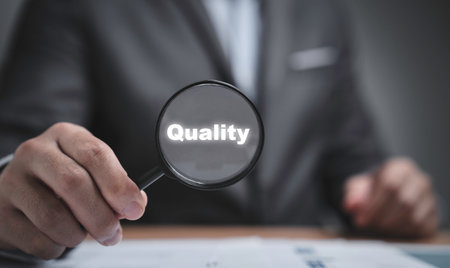 Businessman holding magnifier glass with quality wording for focus quality ISO standard in product...