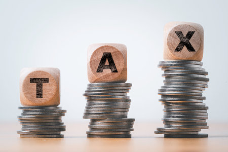 Tax wording print screen on wooden cube block and increasing coins stacking for tax growth and planing concept.の写真素材