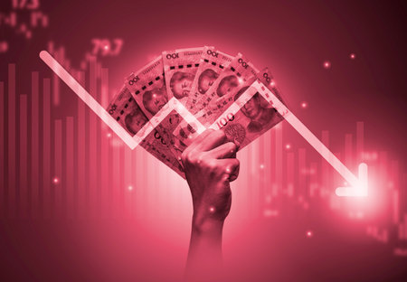 Hand holding Yuan banknote with decreasing arrow and stock market graph chart .It is symbol of china economy crisis concept.の写真素材