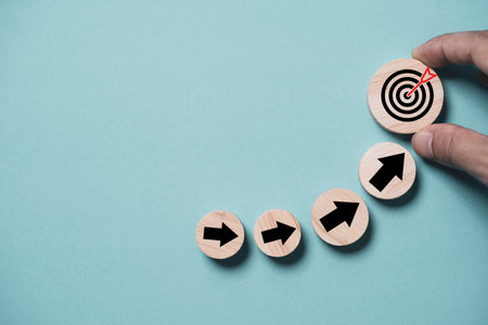 Hand putting virtual target board and up arrow which print screen on wooden round. Business...