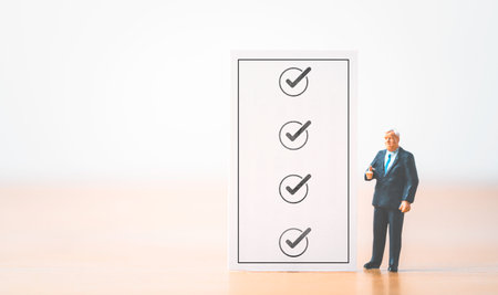Businessman miniature figure standing with check mark sign on checklist sheet for document audit and project approve concept.の写真素材