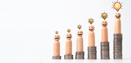 Wooden figure of human standing on increasing coins stack with glowing lightbulb for creative thinking , problem solving and solution can make more money concept.の写真素材