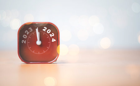 2023 and 2024 on red alarm clock on wooden table with copy space and bokeh , Merry Christmas and...