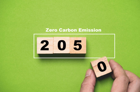 Hand putting wooden block cube of 2050 year from Kyoto Protocol for zero carbon emissions  footprint...