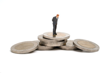 Miniature figure of businessman standing and thinking on coins stacking for analysis and consider investment of business growth concept.の写真素材