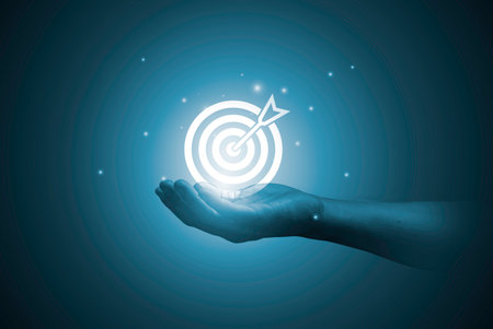 Hand holding dartboard with arrow for setup and give business objective target and goal concept.の写真素材