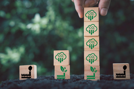 Hand stacking CO2 reducing icon on green factory for decrease CO2 , carbon footprint and carbon credit to limit global warming from climate change, Bio Circular Green Economy concept.の写真素材