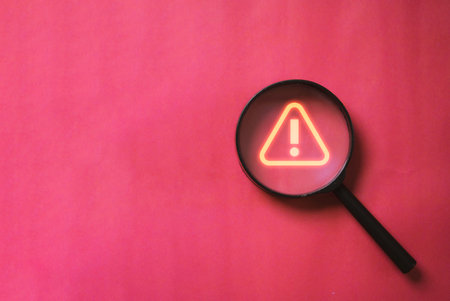 Glowing red triangle caution warning or exclamation sign inside magnifier glass for notification error and maintenance concept.の写真素材