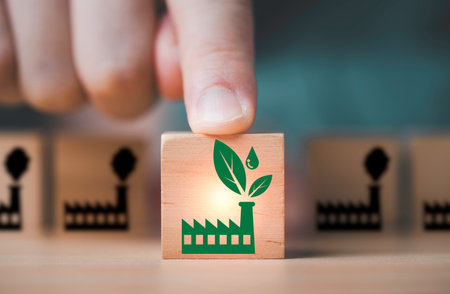 Hand pushing green factory in front of pollution factory for green produce and economy to reduce...