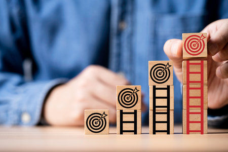 Businessman putting dartboard with arrow on the top of ladder for enhance and achievement setup...