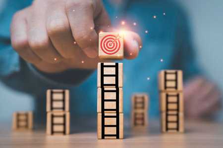 Businessman putting dartboard with arrow on the top of ladder for enhance and achievement setup business objective target goal concept.の写真素材