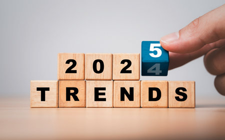 Hand flipping wooden block cube to change from 2024 to 2025 trends for business , fashion and technology trend change concept after new year.の写真素材